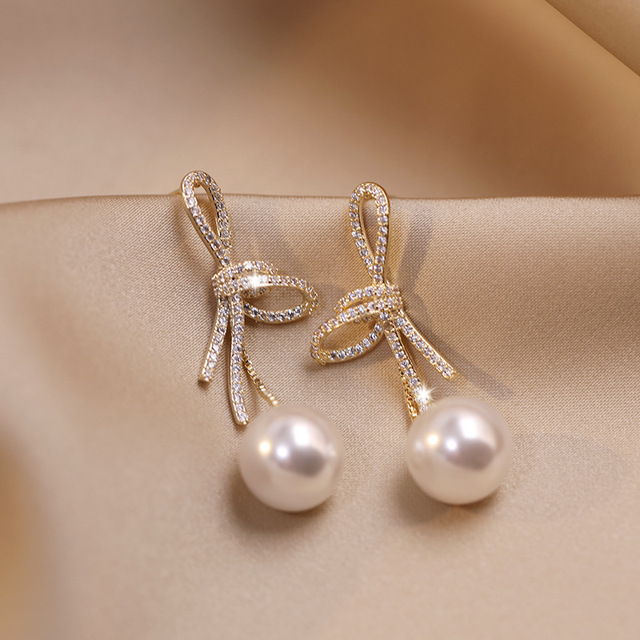 Pearl earrings with a glossy gold bow
